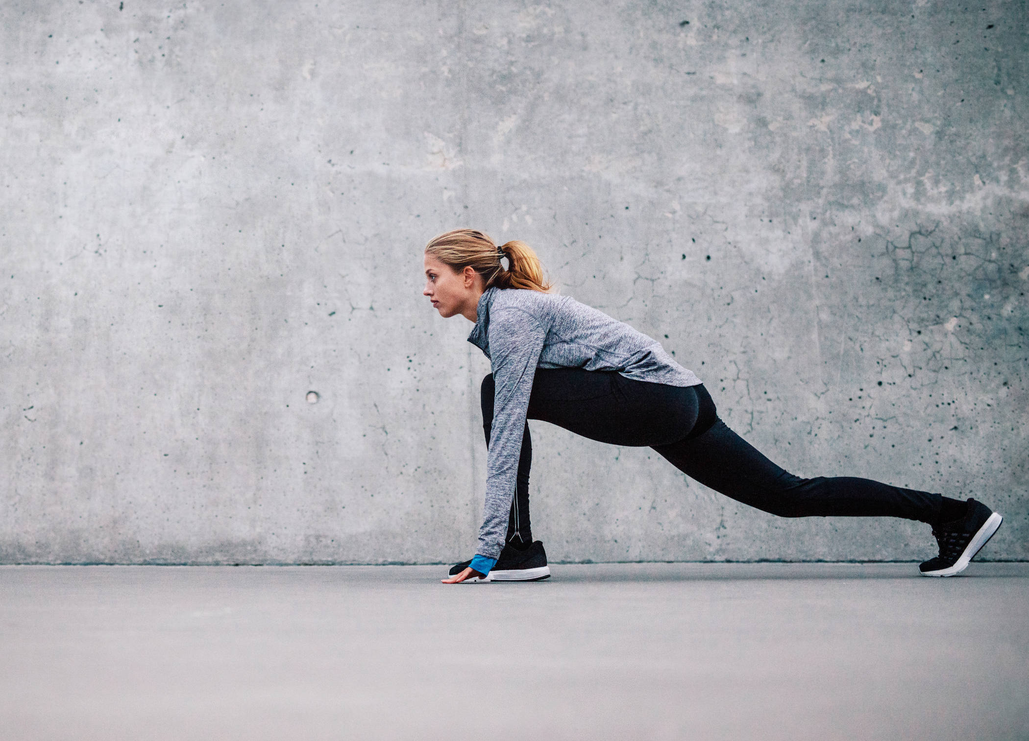 Young attractive cool sporty woman doing crisscross fitness exercise, bicycle crunches, working out on the floor, wearing black sportswear bra and black pants, full length at home or sports center